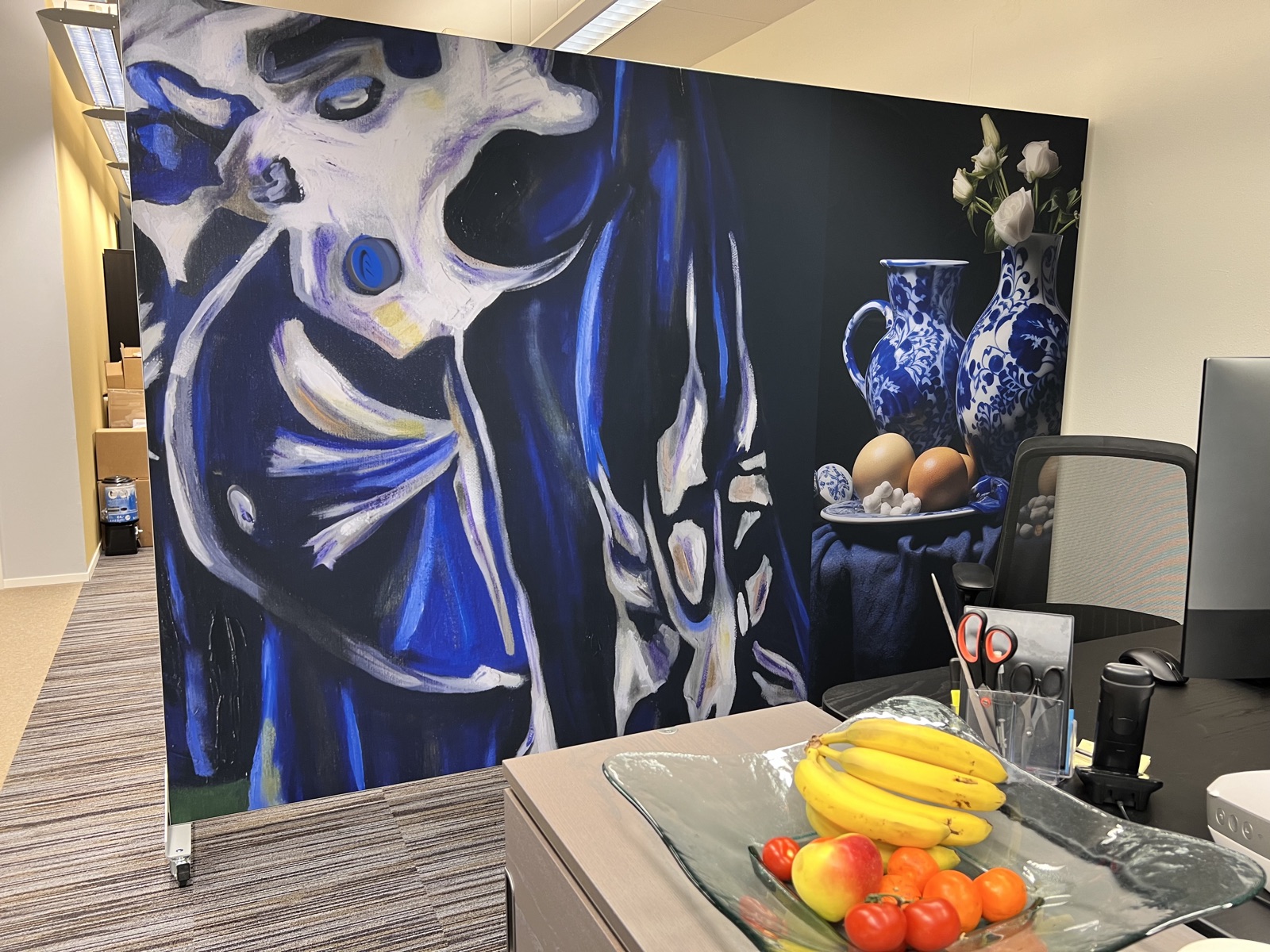 Akoestische room divider op locatie: blauw schilderkunstig motief naast een Delfts blauw stilleven